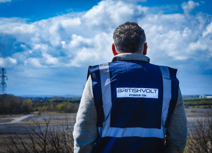 Man in Britishvolt vest looks towards construction site.