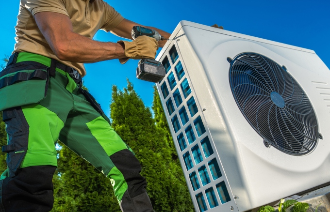 HVAC technician installing a large modern heat pump