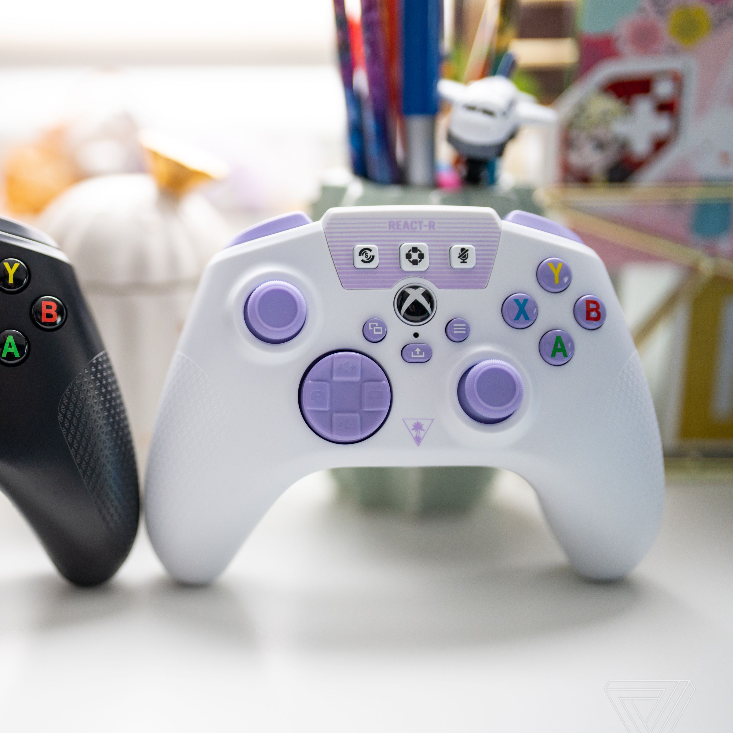 A side-by-side image of the Turtle Beach React-R controllers, black on the left and white / purple on the right.