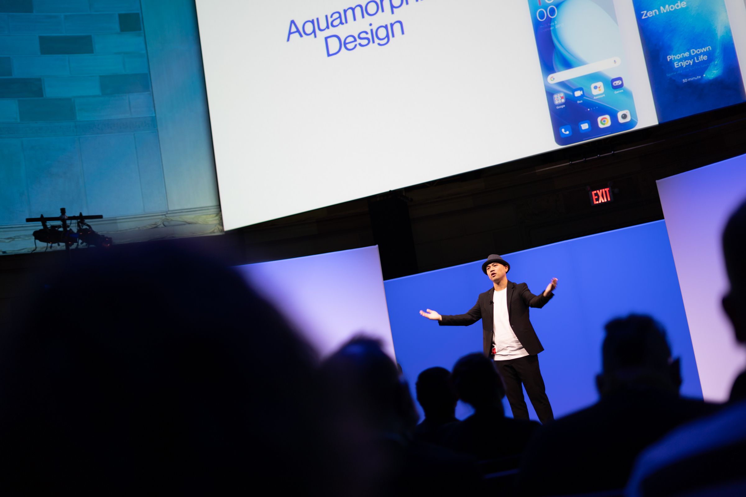 OnePlus executive giving a presentation on stage with the audience in silhouette in the foreground.