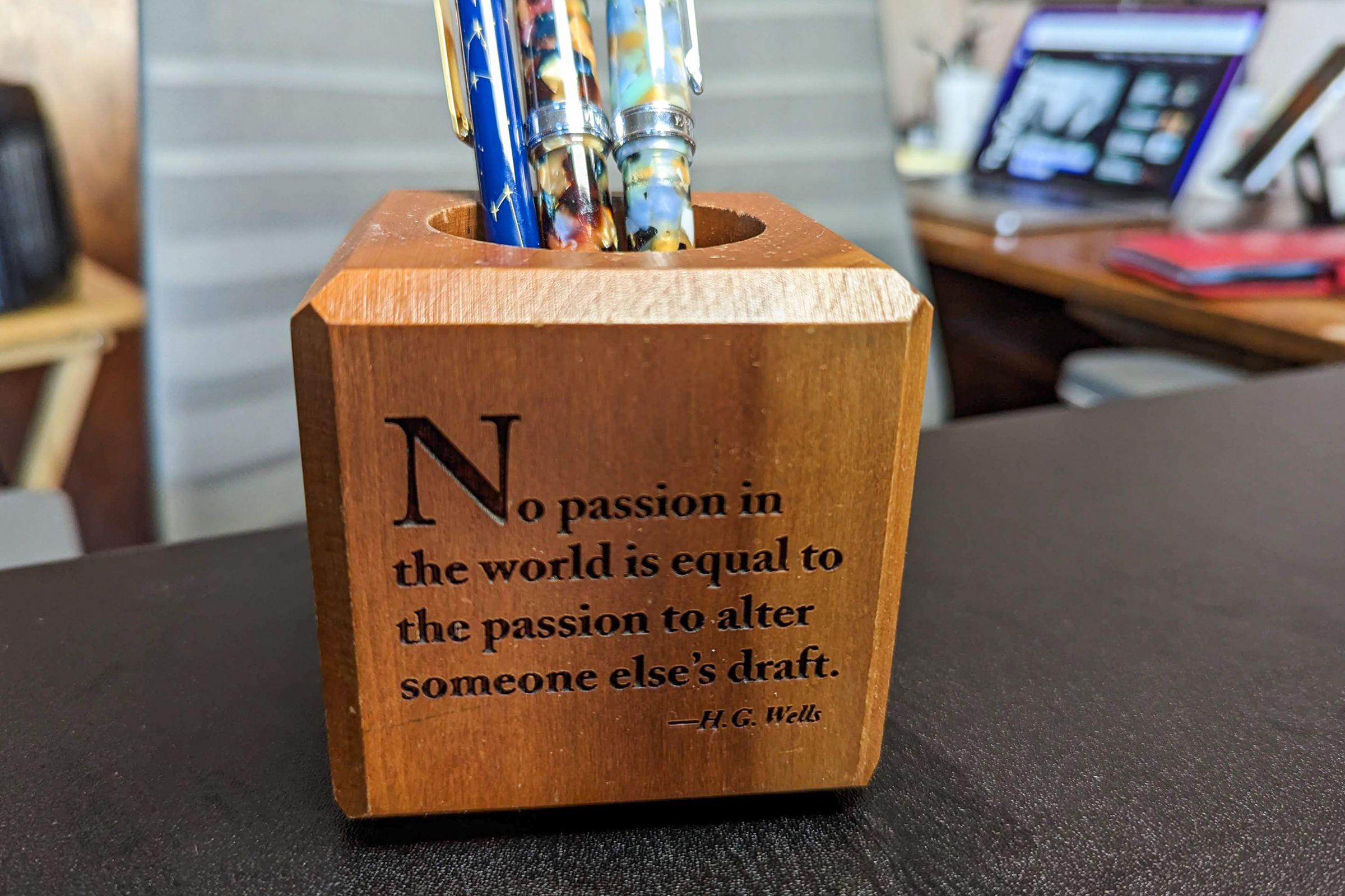 A square wooden pencil holder with a quote that reads 