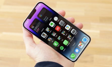 iPhone 14 held in one hand showing the home screen.