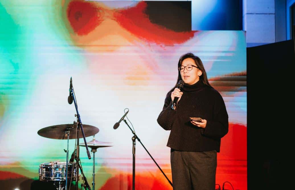 image of NFT literary artist Kalen Iwamoto speaking into a microphone on stage