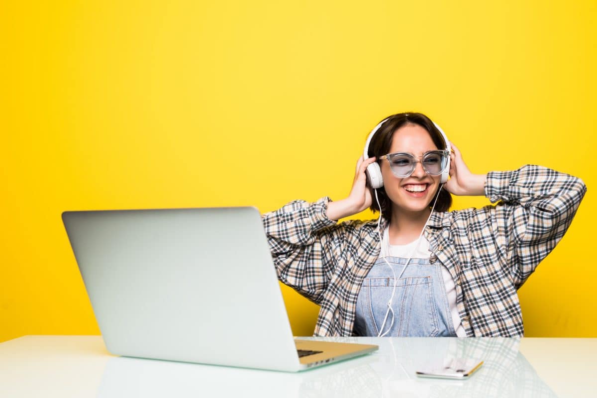 picture of a happy woman listening to music with headphones on a yellow background
