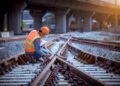 Portrait engineer under inspection and checking construction process railway switch and checking work on railroad station .Engineer wearing safety uniform and safety helmet in work.