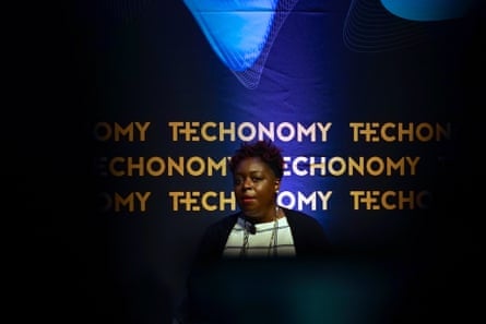 Woman speaking at a lectern with Technomy written on a blue background behind her.