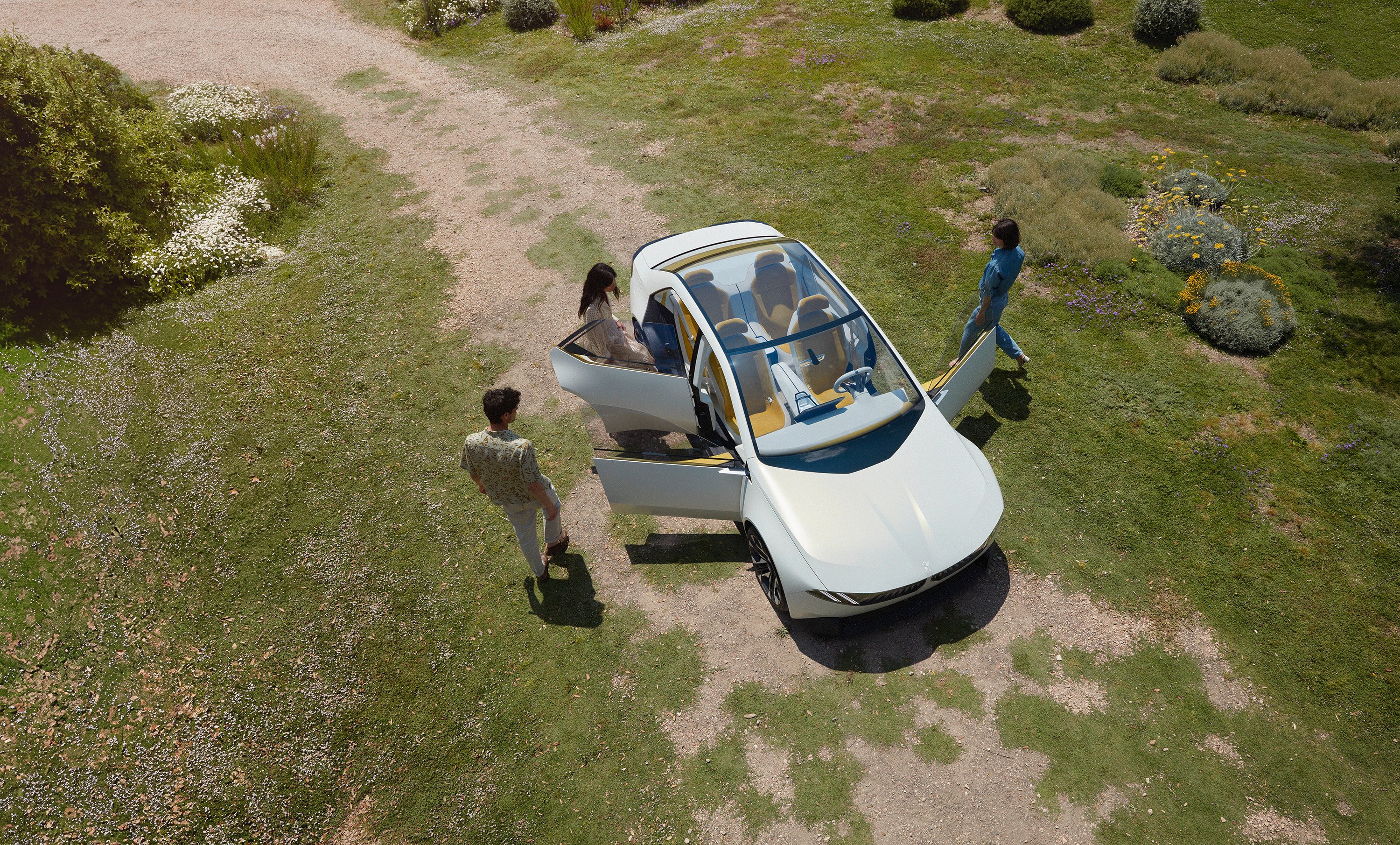 BMW Vision Neue Klasse - white concept car seen from aerial view. people getting into the car.