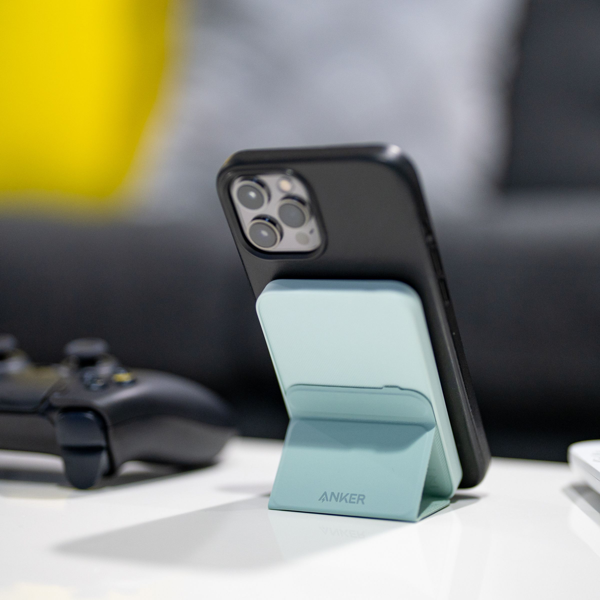 Anker's Magnetic Battery 621 (MagGo) holds an iPhone with its stand on a desk.