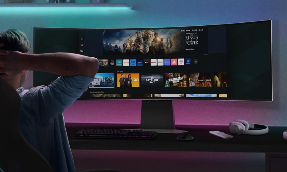 Product lifestyle image of young man crossing his arms behind his head while looking at ultra wide monitor.