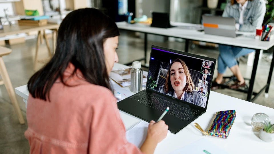 A person sitting at a table, having a video call with another person on the Acer Swift Edge 16. Open office workspace.