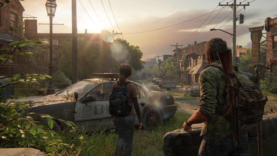 Screenshot of The Last of Us Part I. Joel and Ellie walk among abandoned cars in a small abandoned town.