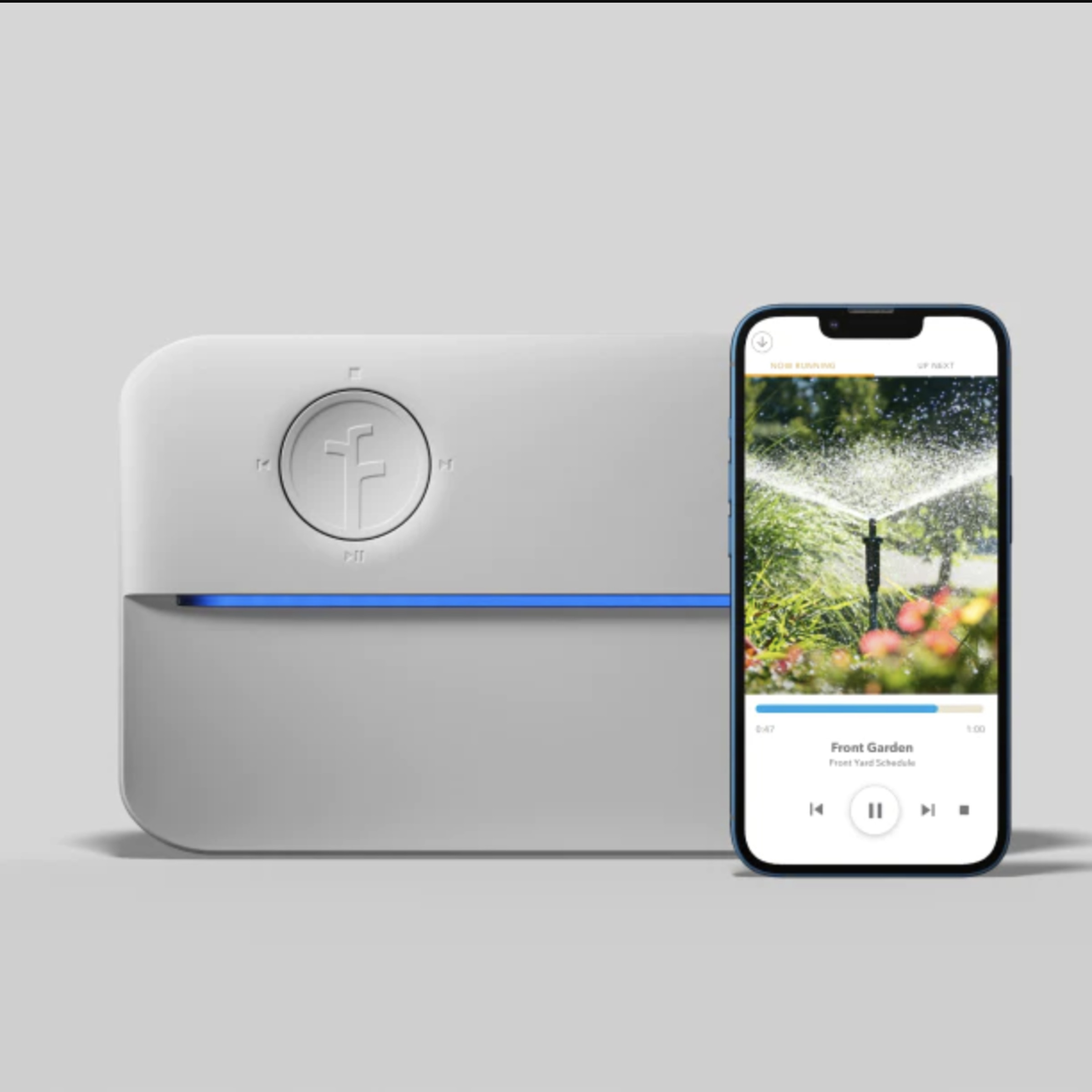 Rachio sprinker controller, a boxy object that’s white with a blue streak running through it lengthwise, and a phone with the app on it.