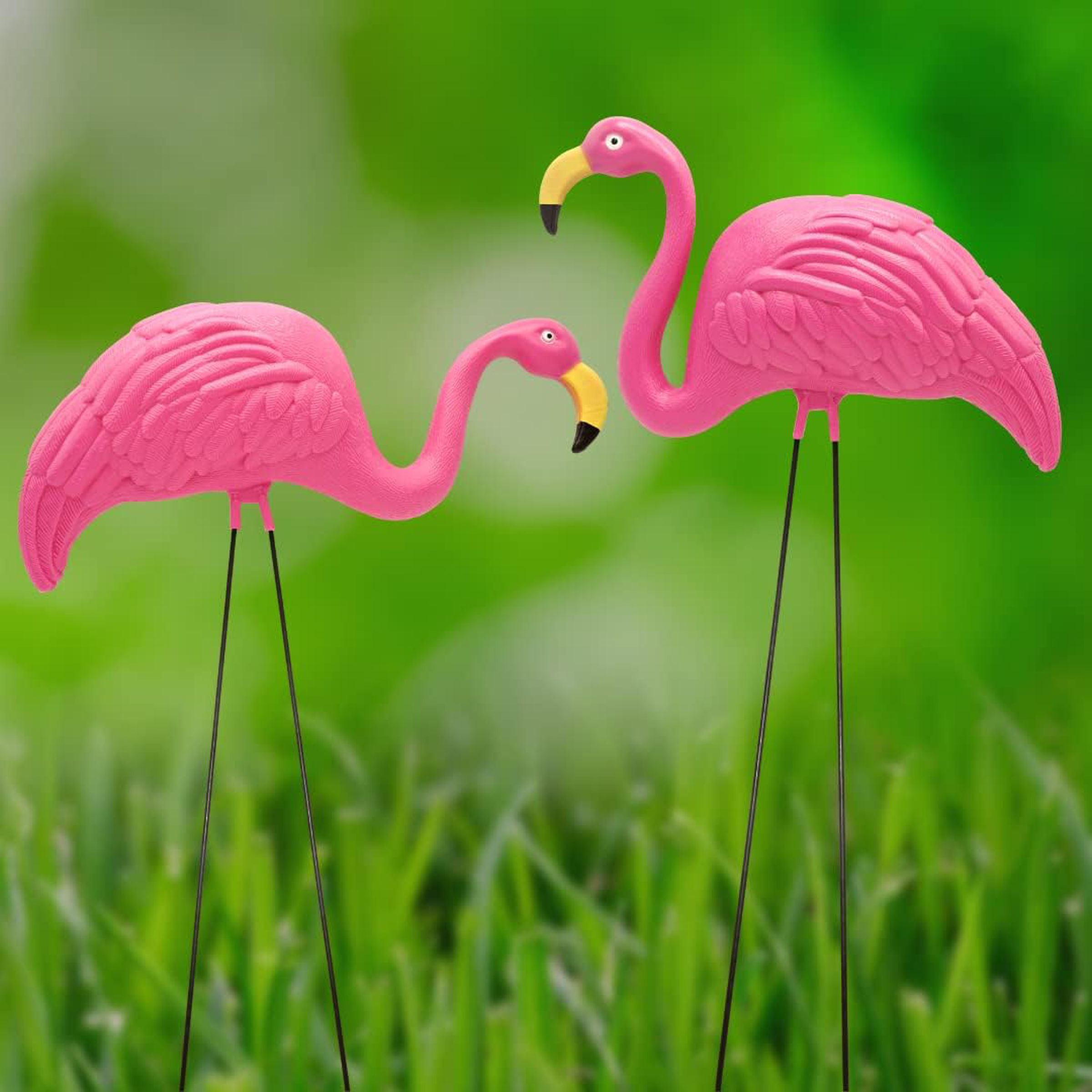 Dos flamencos rosados ​​de plástico sobre un césped verde.