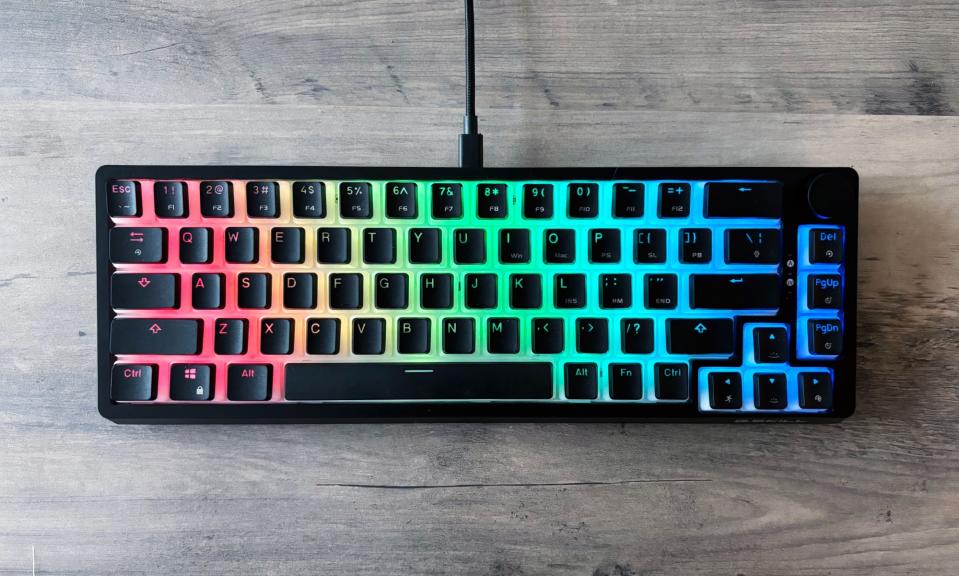 The G.Skill KM250 RGB gaming keyboard rests on a light brown wooden table.