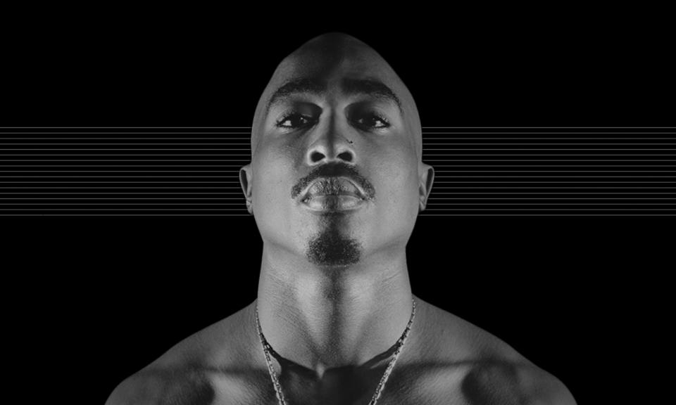 Photo of the late Tupac Shakur, looking at the camera against a black background with subtle horizontal gray lines.