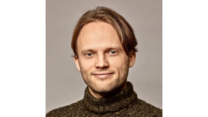 Headshot of former OpenAI alignment head Jan Leike.  Smiles on a grayish brown background.