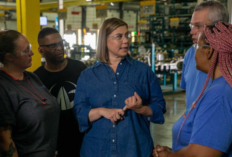 Campaign photo of US Representative Elissa Slotkin.  She is in a factory, wearing protective glasses, talking to several workers.