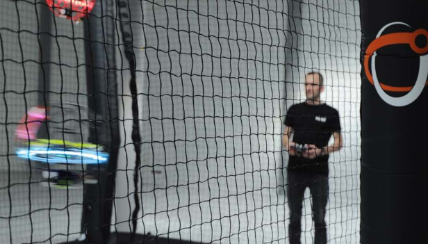 A drone pilot directs a drone at a drone soccer game.