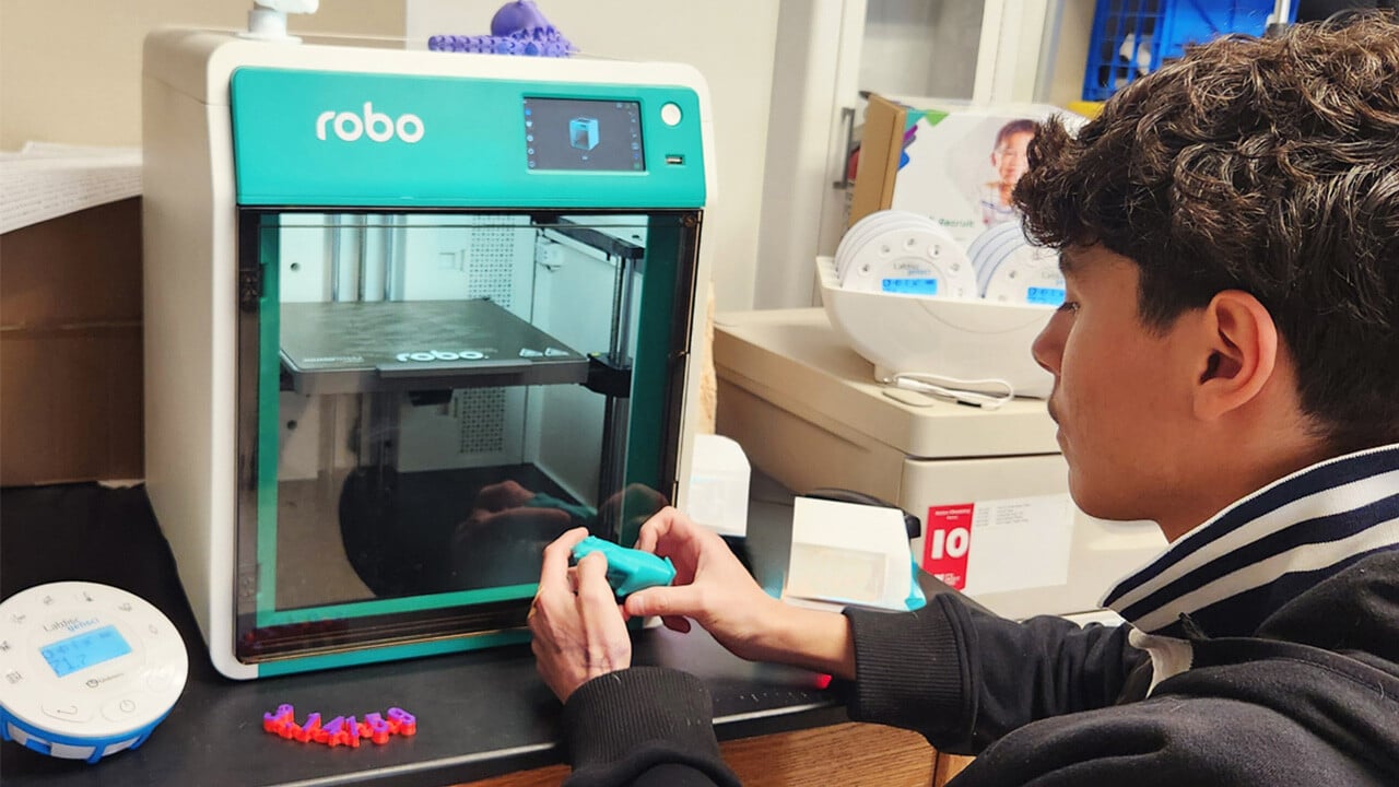 A student removes a 3D printed pig from the Boxlight Robo E4 3D printer