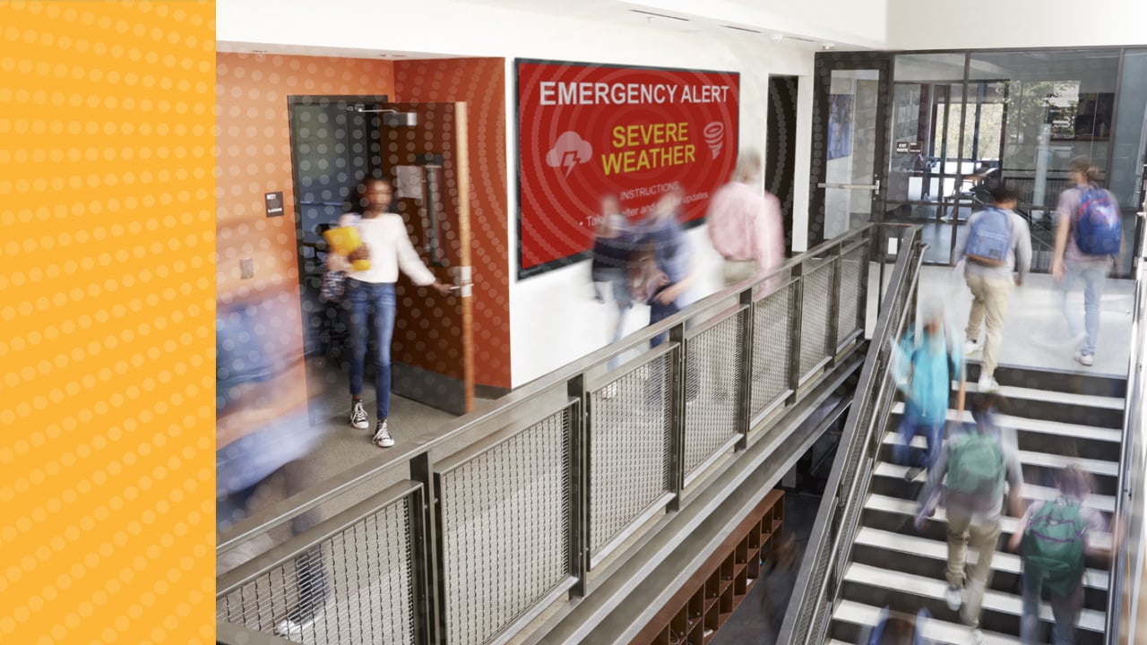 Busy hallway with Boxlight digital signage presenting an on-screen emergency alert message via the Attention campus communication solution.