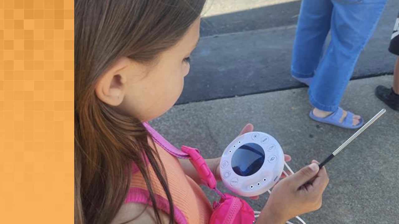 Young student holding an Xploris and looking at data on screen. Also holding a temperature measuring tool.