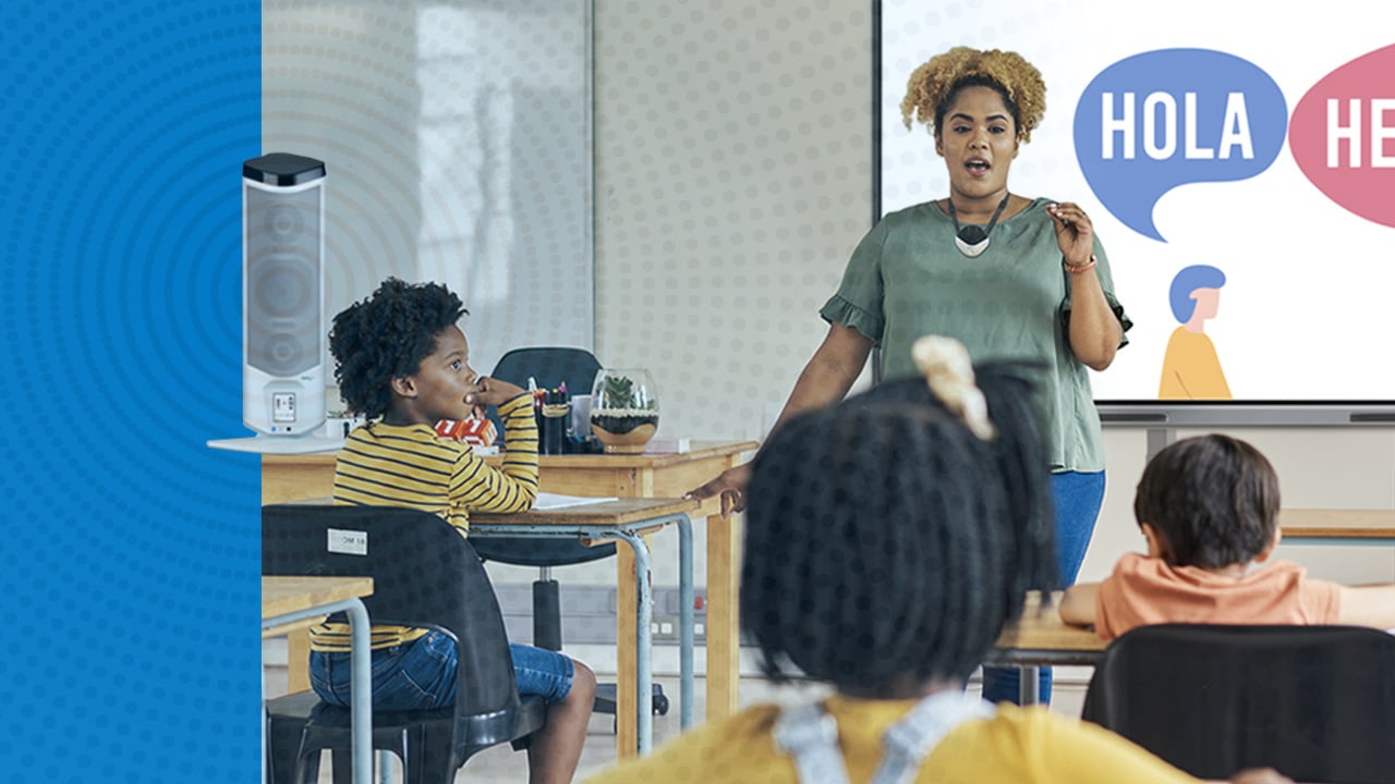 Teacher in front of class giving a Spanish lesson. The Juno classroom sound system is shown in the box.