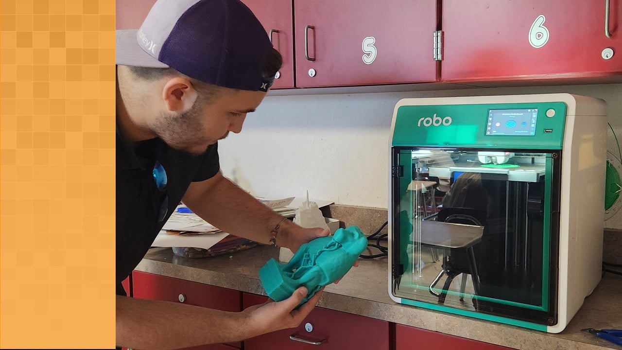 A teacher holds a 3D printed replica of an ancient monkey god after printing it with the Robo E4 3D printer.