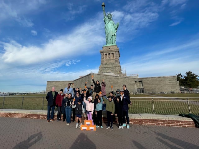 Students and facilitators pose for a photo in front of the Statue of Liberty.