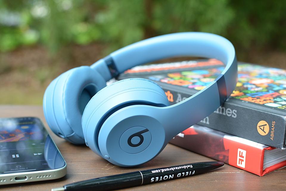 Beats Solo 4 laying on two books with an iPhone to the left and a black pen in the foreground. 