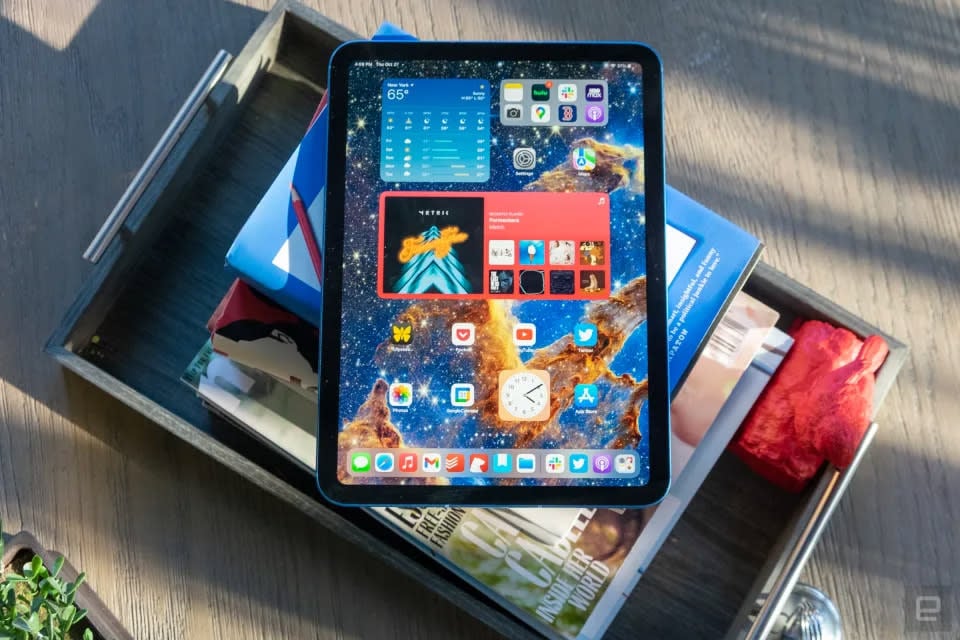 The 10th generation iPad sits on a stack of books. It looks pretty in the dappled afternoon sun. 