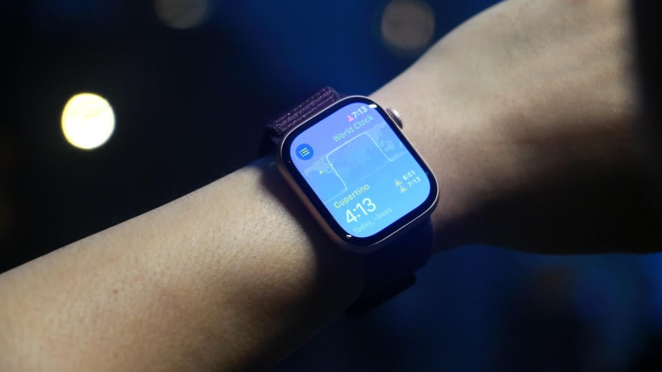 A person wears the Apple Watch Series 10 on their wrist. Displays a blue screen with the time and other widgets. 