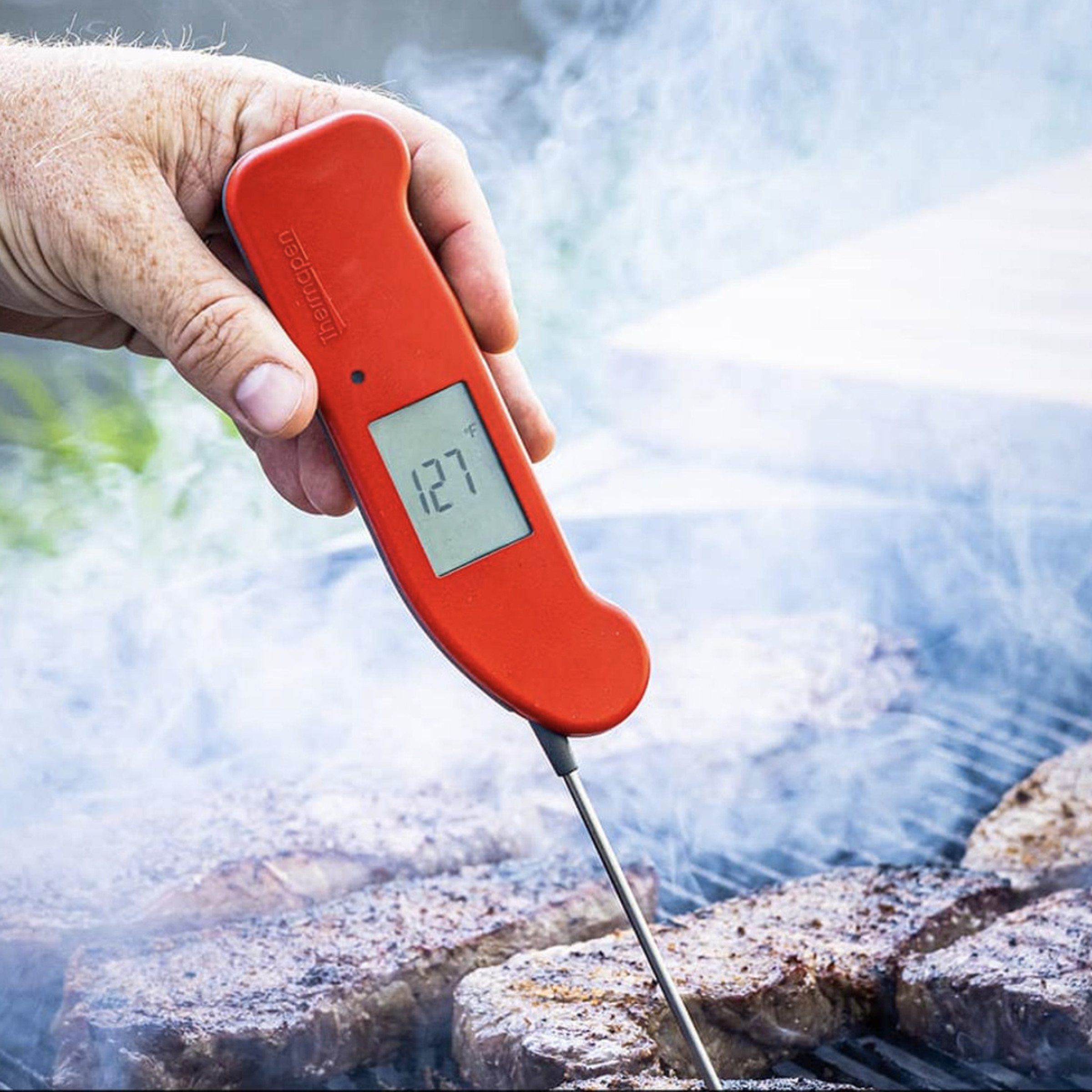 Mano sosteniendo el termómetro Thermapen One en un filete a la parrilla.