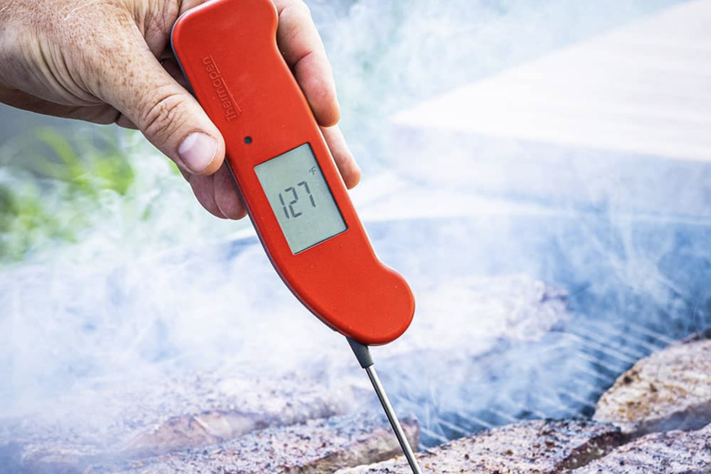 Mano sosteniendo el termómetro Thermapen One en un filete a la parrilla.