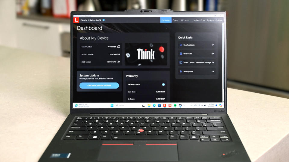 El Lenovo ThinkPad X1 Carbon (12.ª generación) con la pantalla y el teclado frente a la cámara. En su pantalla está el panel Think de Lenovo que muestra información sobre el dispositivo, incluida la actualización del sistema y la garantía.