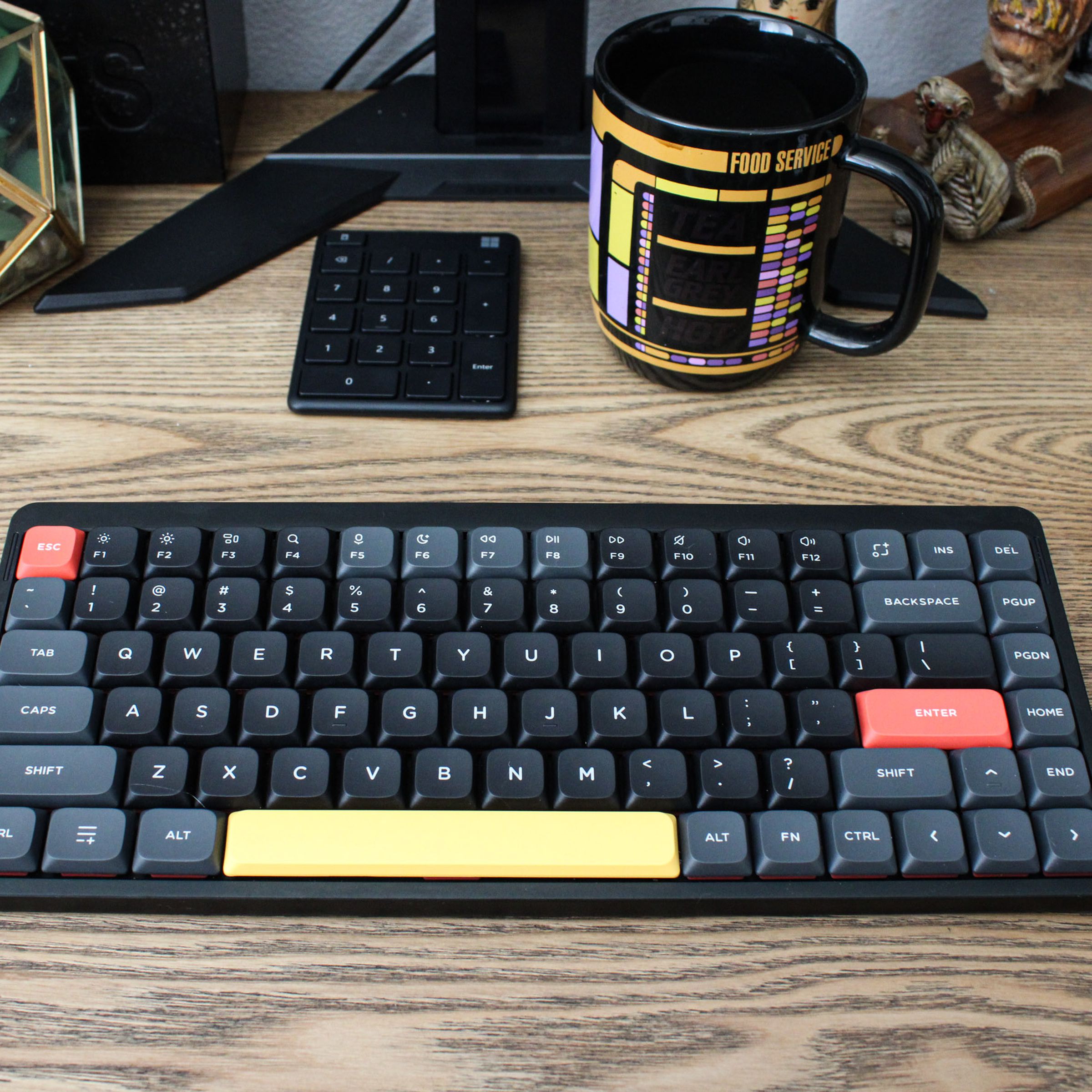 A Nuphy Air75 V2 keyboard with black, gray, red and yellow keys on a desktop.