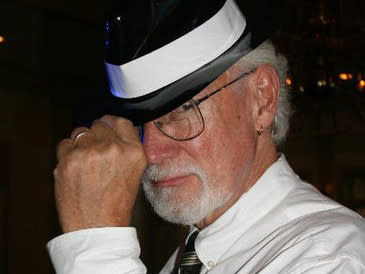 Greg Hildebrandt with an elegant black hat, which he puts on while looking at the camera with his sexiest face.