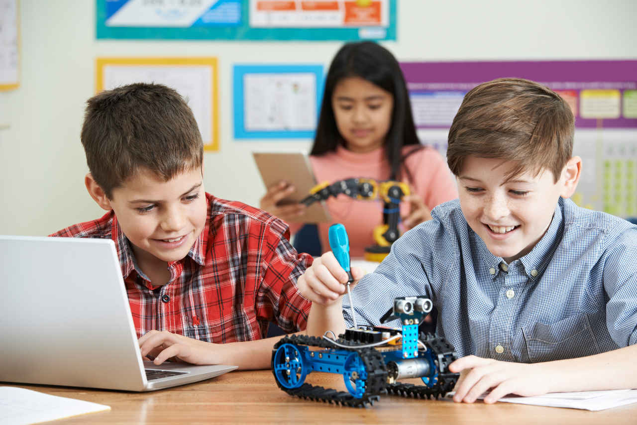 Two boys and a girl working with robots in the classroom.