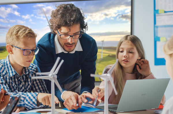 Teachers with three students, laptop and model of windmills.