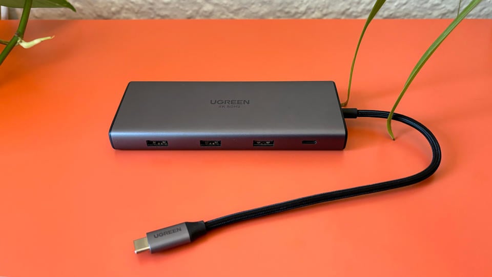 The UGreen Revodok Pro 109 USB-C hub sits on an orange background. 