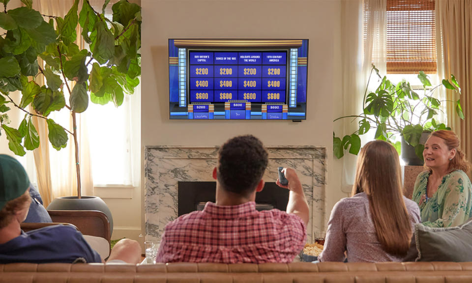 Lifestyle product image of a group of friends in a room playing Jeopardy! on your television.